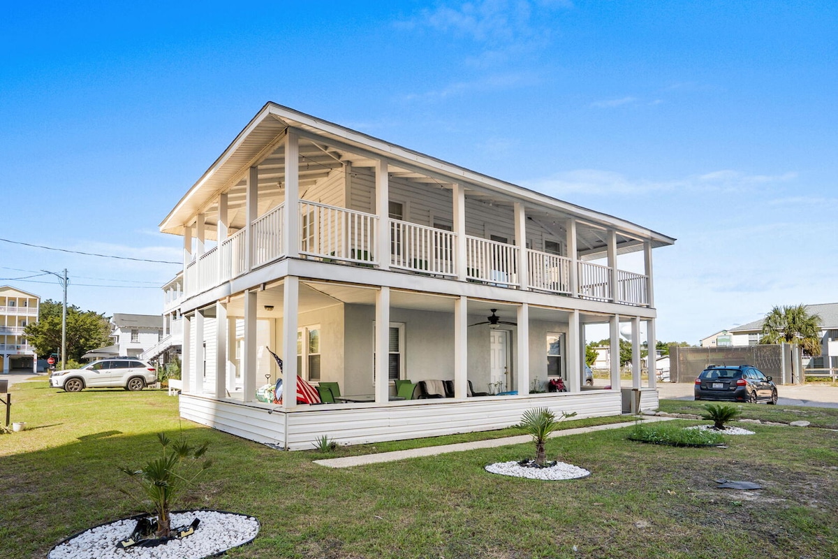 The white double-porch beach house on its quiet second-row street