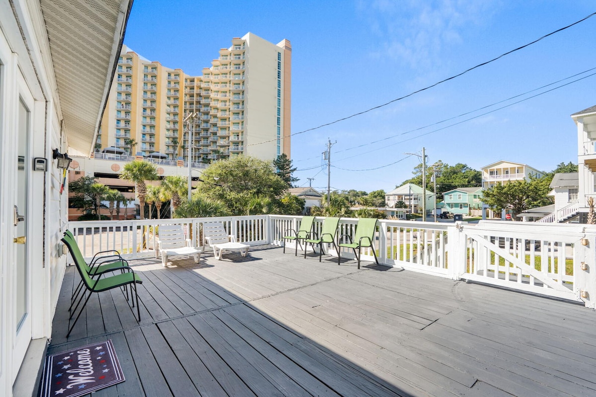 The upper covered porch with outdoor seating looking over the neighborhood toward the oceanfront
